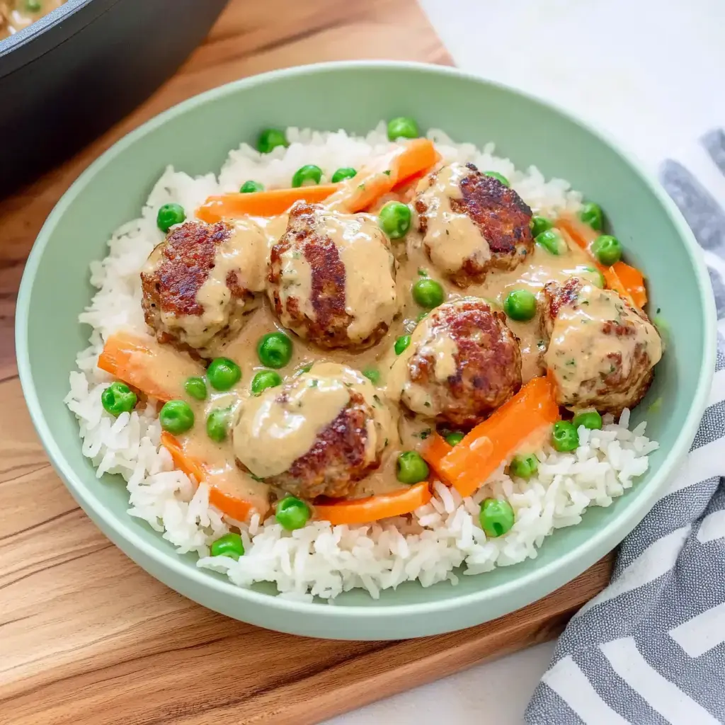 Reis und Hackbällchen in einer sahnigen Sauce, dazu Möhren und Erbsen – sieht superlecker aus.