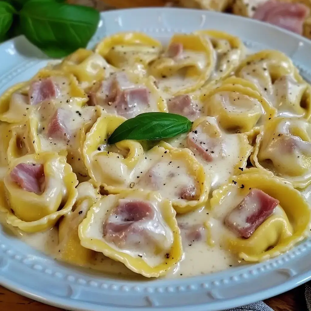 Schüssel Tortellini in cremiger Sauce, mit frischem Basilikum obendrauf.