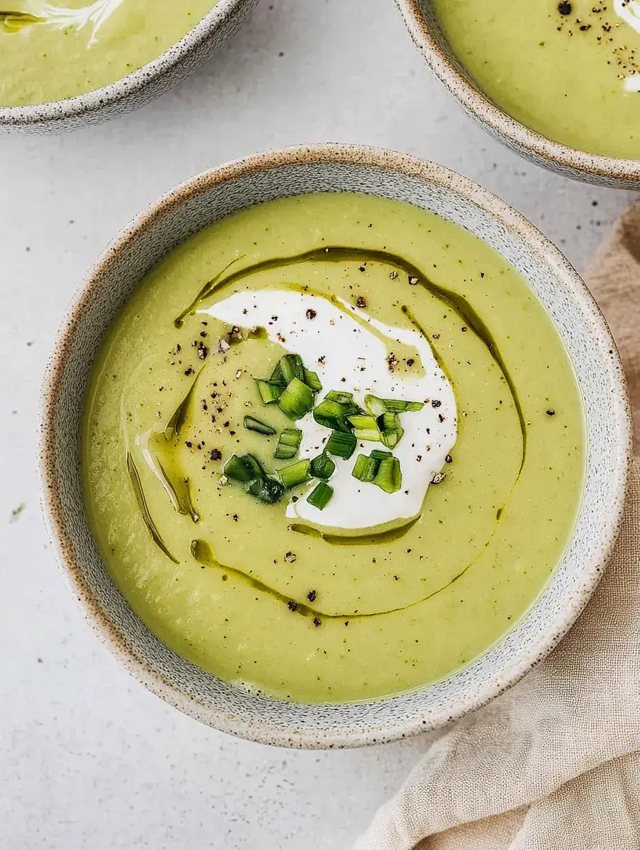 Eine Schale voll leuchtend grüner Cremesuppe, obenauf etwas Sauerrahm, frische Schnittlauchstreifen und ein Hauch Olivenöl.