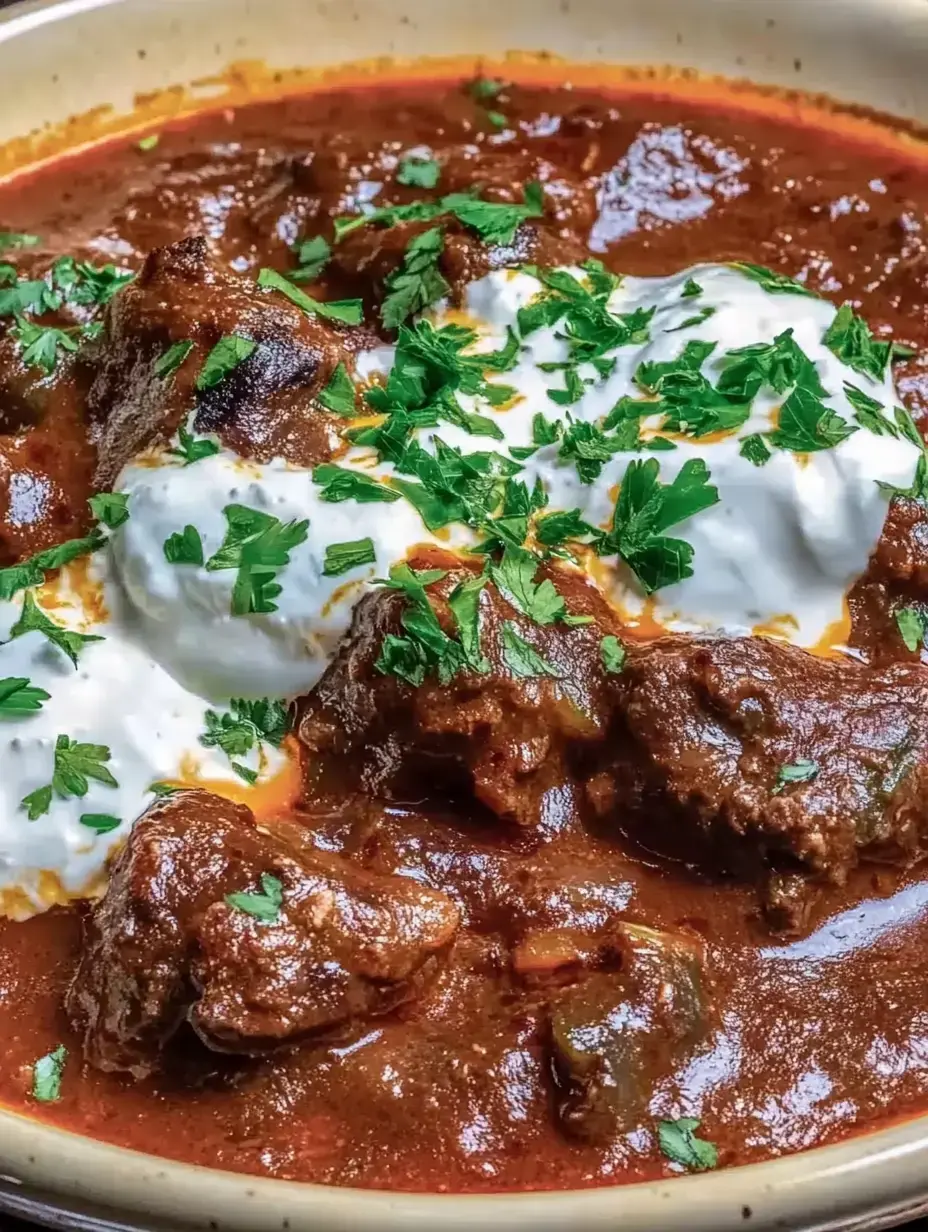 Ein deftiges Fleischgericht in sämiger Sauce, getoppt mit frischem Koriander und einem Löffel Joghurt.