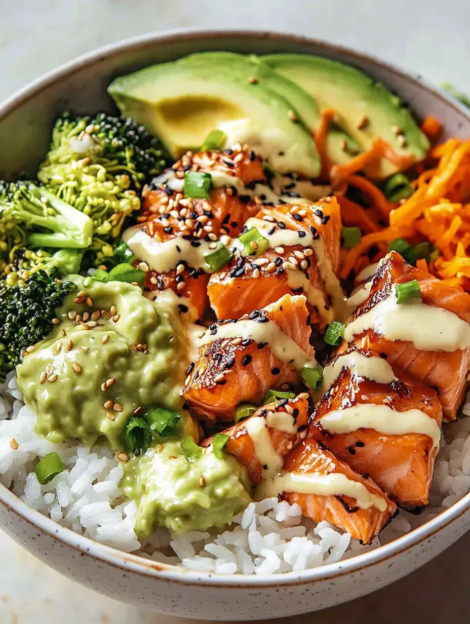 Eine Schüssel mit Reis, gegrilltem Lachs, Brokkoli, Avocadoscheiben, geriebenen Karotten, Guacamole und einer cremigen Sauce, garniert mit Sesam und Frühlingszwiebeln.