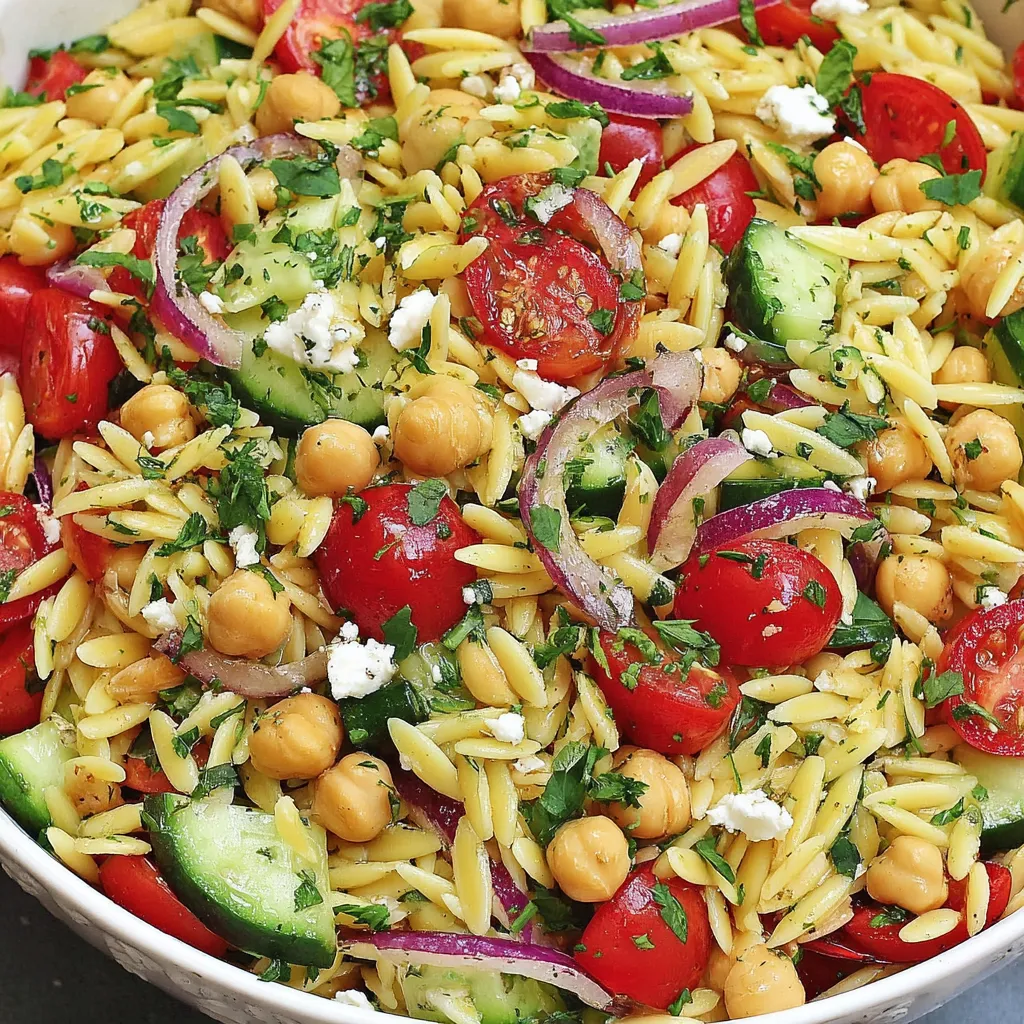 Ein weißer Becher mit einer Mischung aus Kichererbsen, Orzo und Salat.