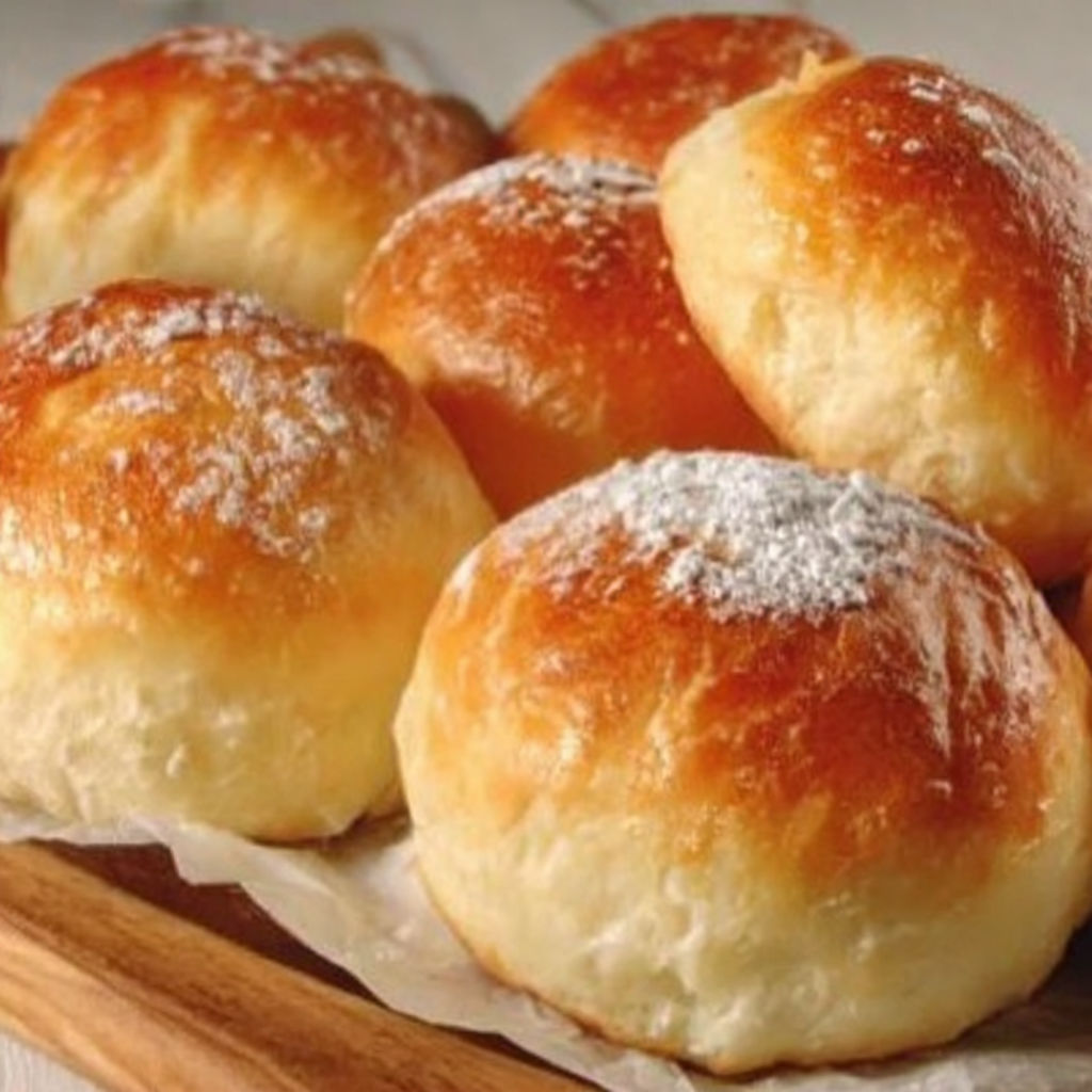 A plate of fluffy, white, sugar-covered bread rolls.