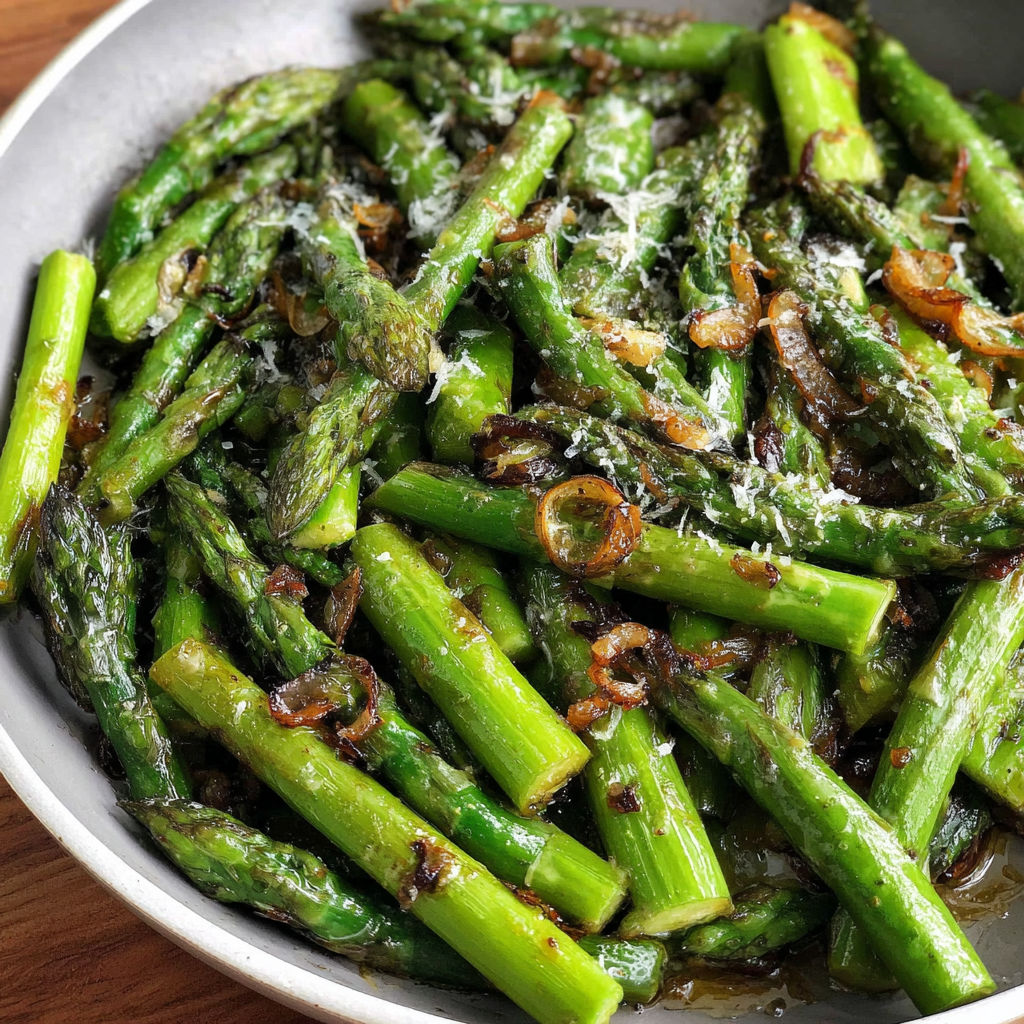 A pan of cooked asparagus with cheese and onions.