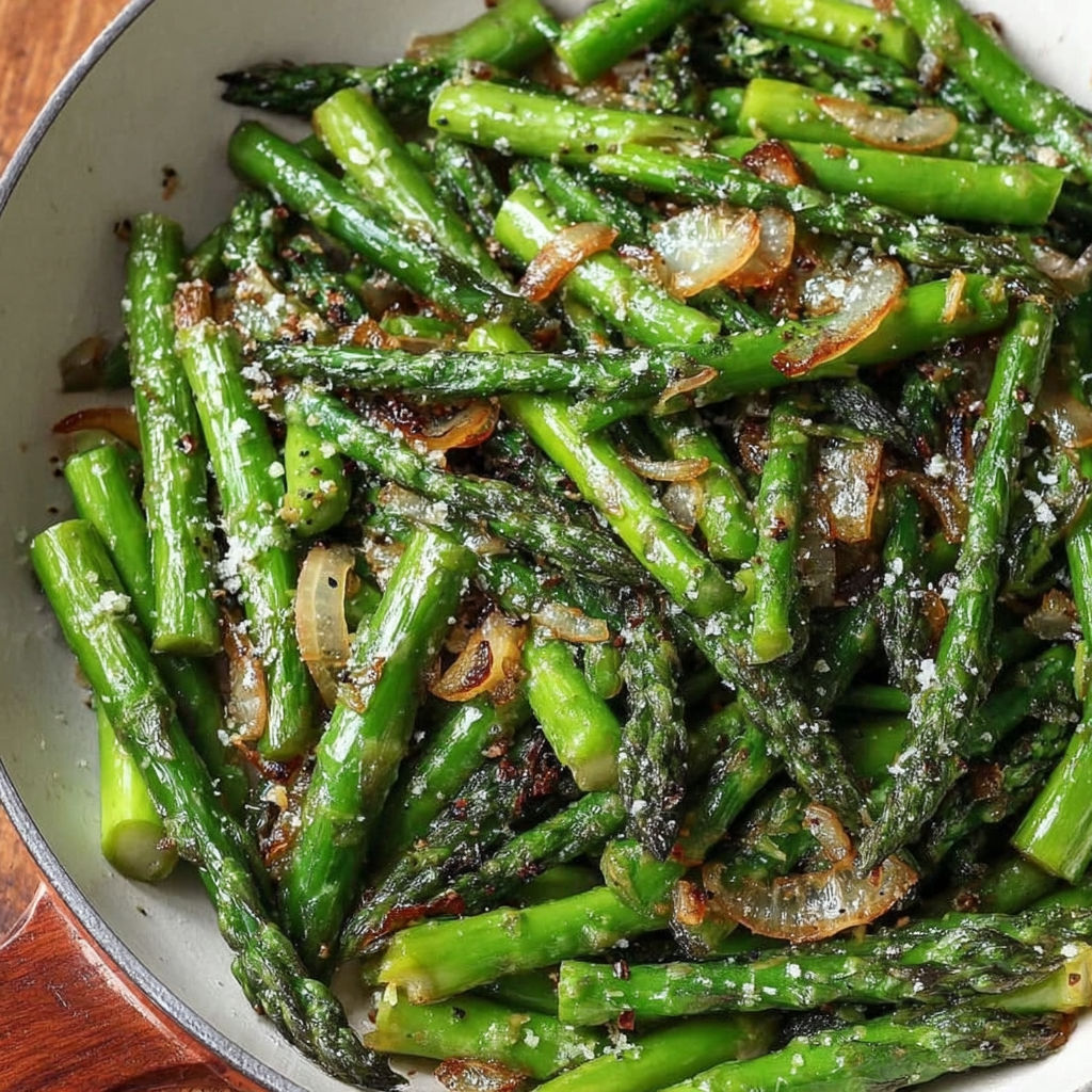 A bowl of cooked asparagus with onions and spices.