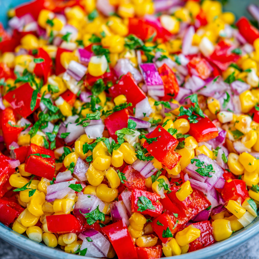 A bowl of vegetables including corn, tomatoes, onions, and peppers.