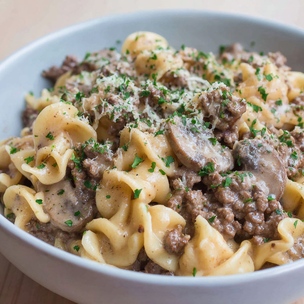 A bowl of beef stroganoff with noodles and mushrooms.