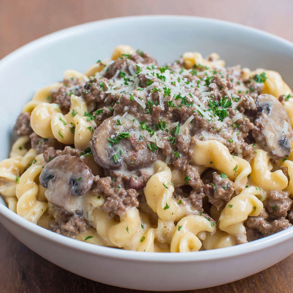 A bowl of beef stroganoff with mushrooms and cheese.