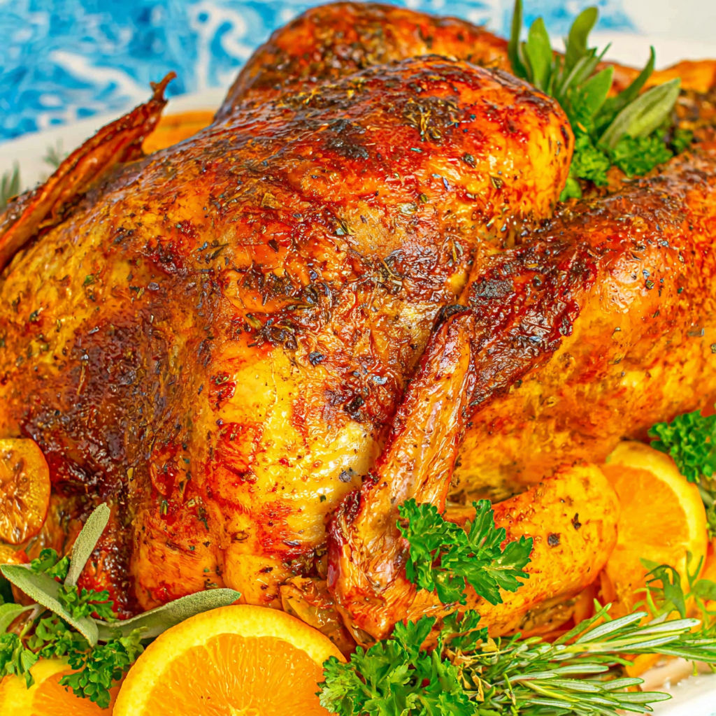 A juicy oven roasted turkey with a slice of orange on top.
