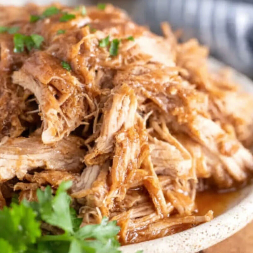 A close up of a crock pot filled with pulled pork.