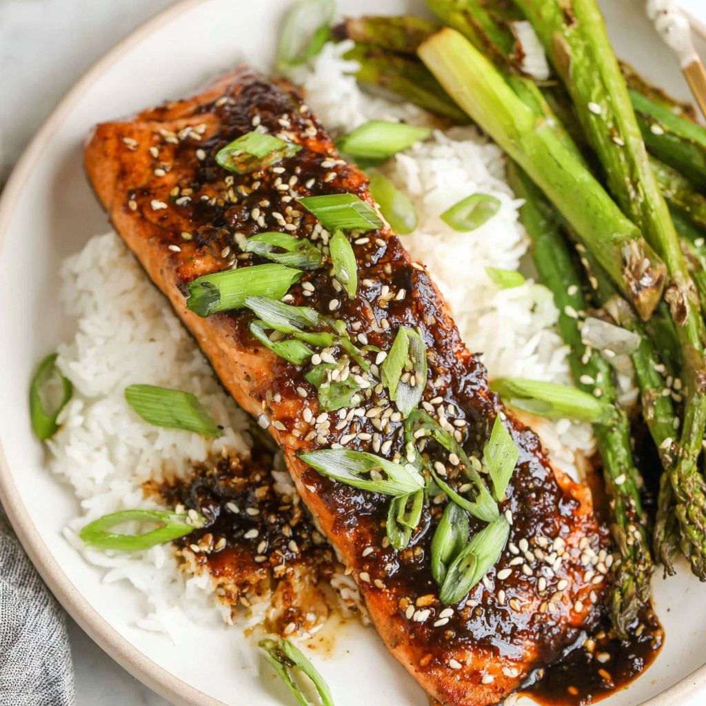 A plate of food with salmon, rice, and asparagus.
