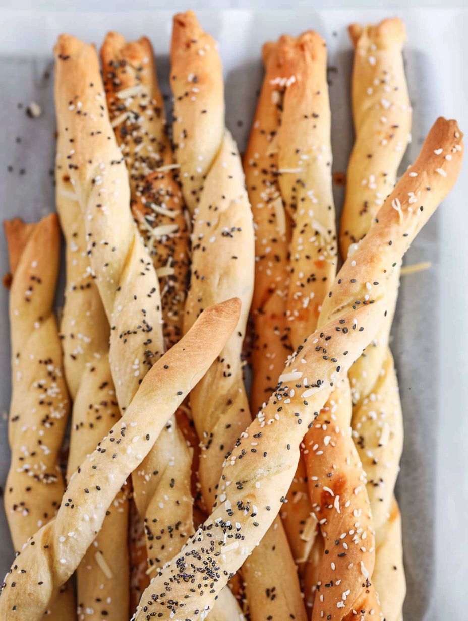 Breadsticks with sesame seeds on a tray.