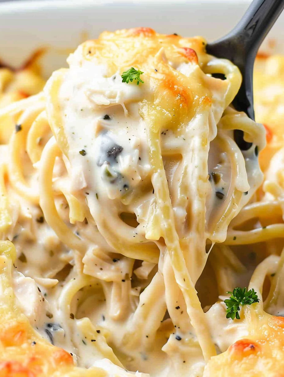 A fork is holding a piece of chicken tetrazzini.