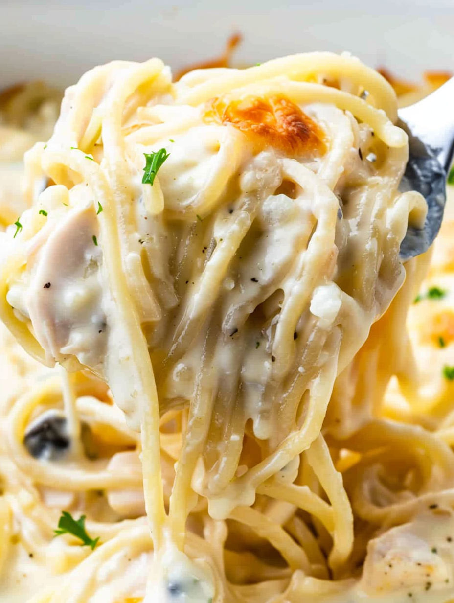 A fork is holding a piece of chicken tetrazzini.