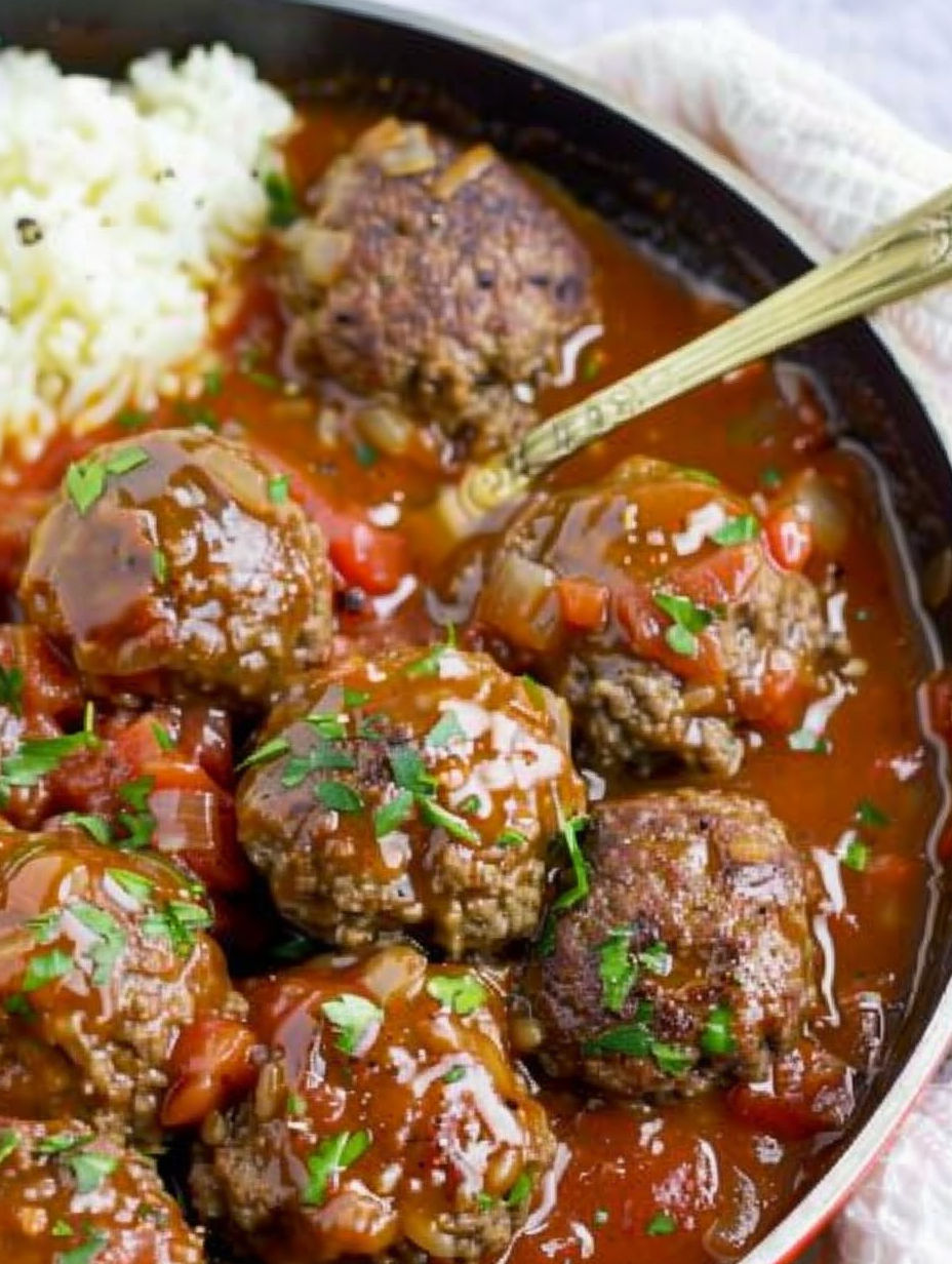 A plate of meatballs in a brown sauce.
