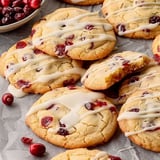 A plate of cookies with white icing and red berries.