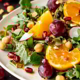 A salad with oranges, cherries, and greens.