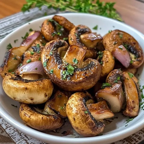 Ein Schüssel mit gebratenen Champignons und Zwiebelstücken, garniert mit frischen Kräutern.