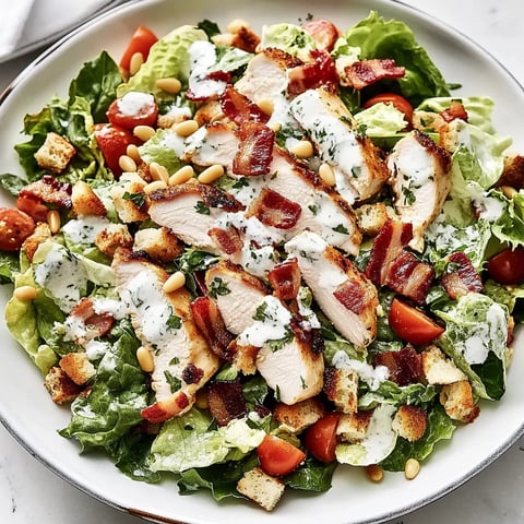 Ein bunter Salat mit Hähnchen, Tomaten, Salatblättern und Speck.