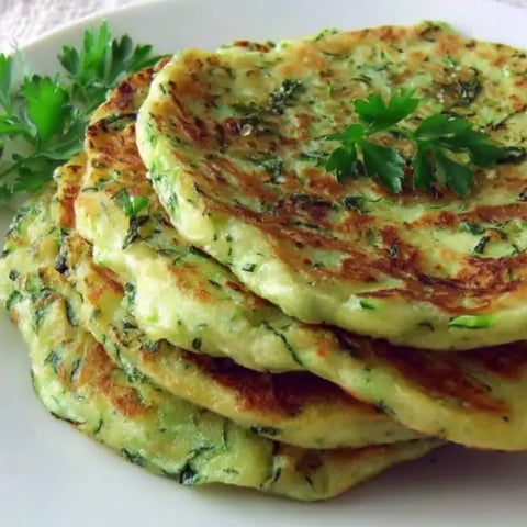 Zucchini-Pfannkuchen auf einem weißen Teller.