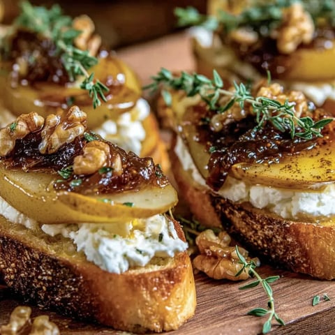 Zwei Crostini mit Karamellisierten Birnen und Ziegenkäse auf einem Holzblock.