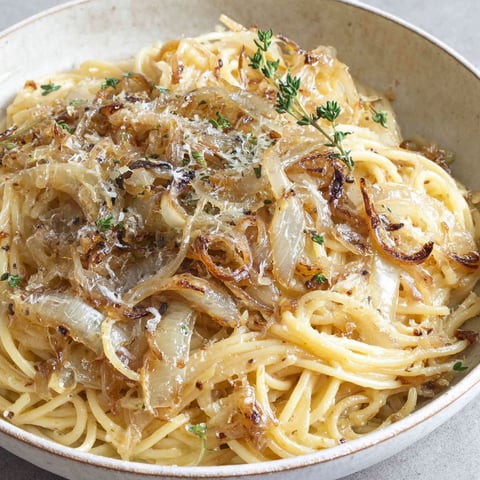 A bowl of pasta with onions and cheese.