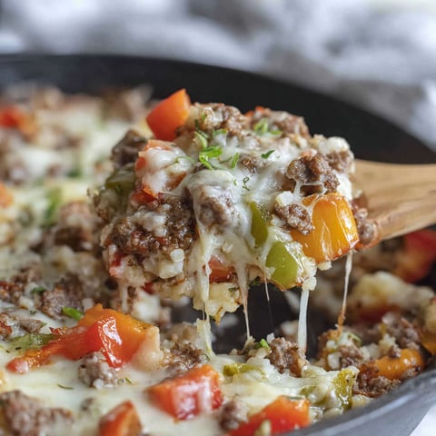A skillet with a fork in it filled with meat and vegetables.