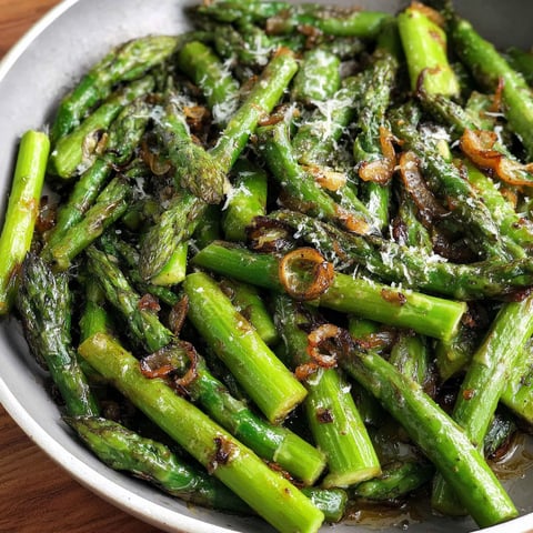 A pan of cooked asparagus with cheese and onions.
