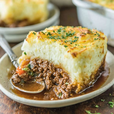 A slice of shepherd's pie with a spoon on top.