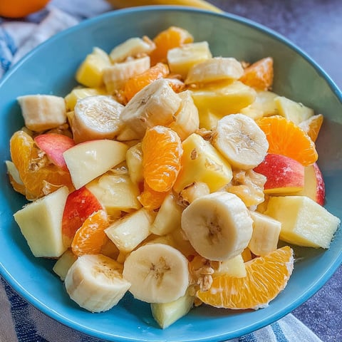 A bowl of fruit with bananas, oranges, and apples.