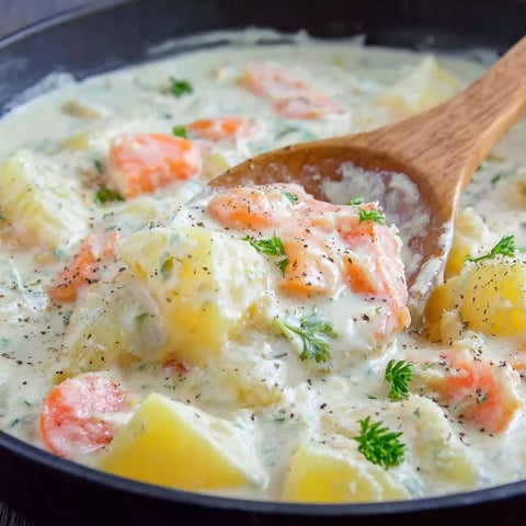 A bowl of soup with carrots and potatoes.