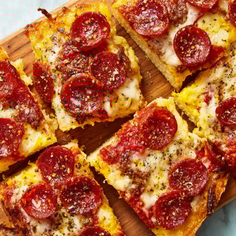 Slices of pepperoni pizza on a wooden cutting board.