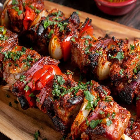 A wooden platter with grilled meat and vegetables.