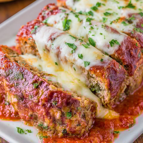 A plate of Italian meatloaf with cheese and sauce.