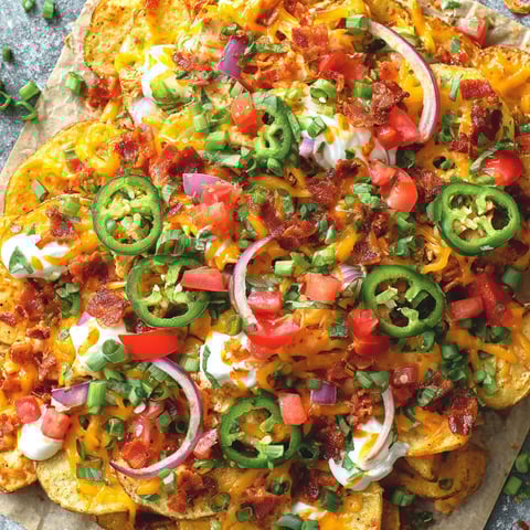 A plate of nachos with cheese, tomatoes, and jalapenos.