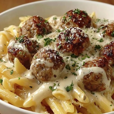 A bowl of pasta with meatballs and cheese.