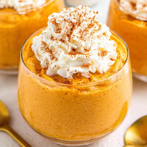 A glass of pumpkin mousse with whipped cream.