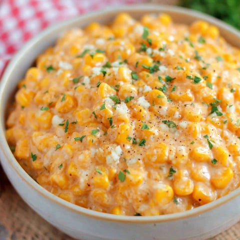 A bowl of creamed corn with green onions on top.
