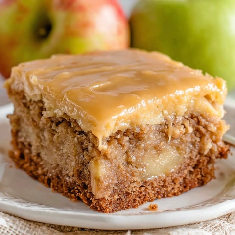A slice of apple dapple cake on a white plate.
