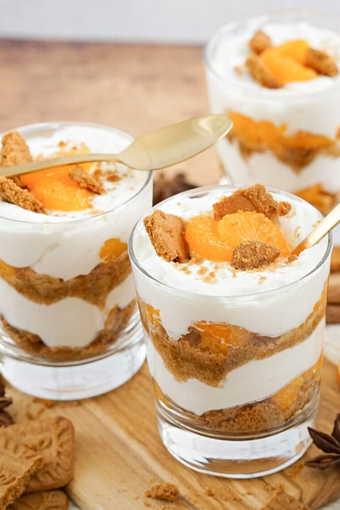 A glass of orange cream with cookies on top.