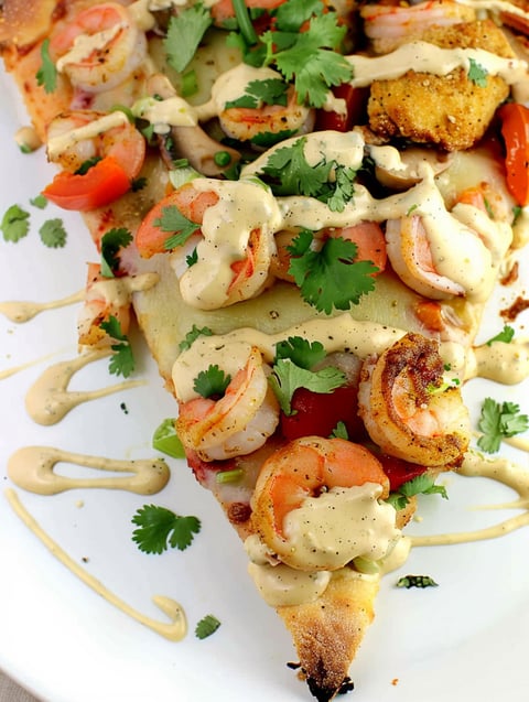 A slice of pizza with shrimp and sauce.