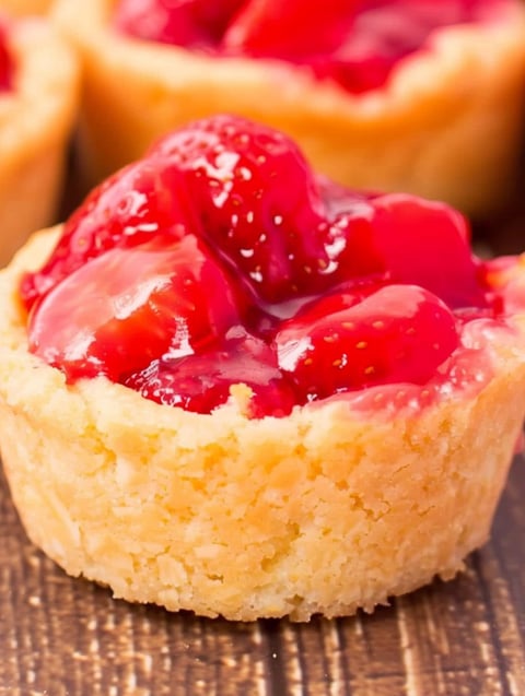 A close up of a cookie with strawberry jam in it.