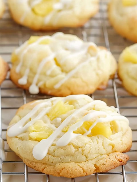 A tray of cookies with white icing and pineapple.