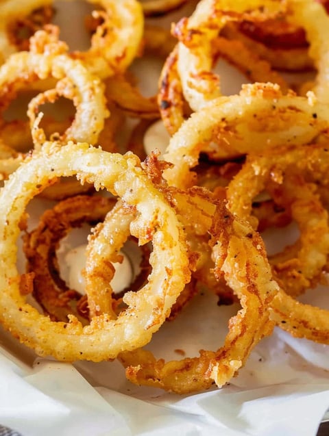 A plate of onion rings with a dipping sauce.