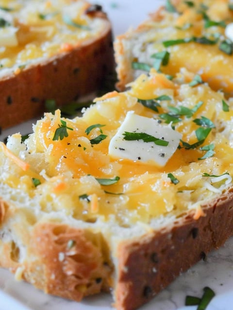 A slice of garlic toast with cheese and herbs on top.