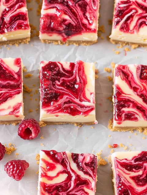 Raspberry swirl cheesecake bars on a table.