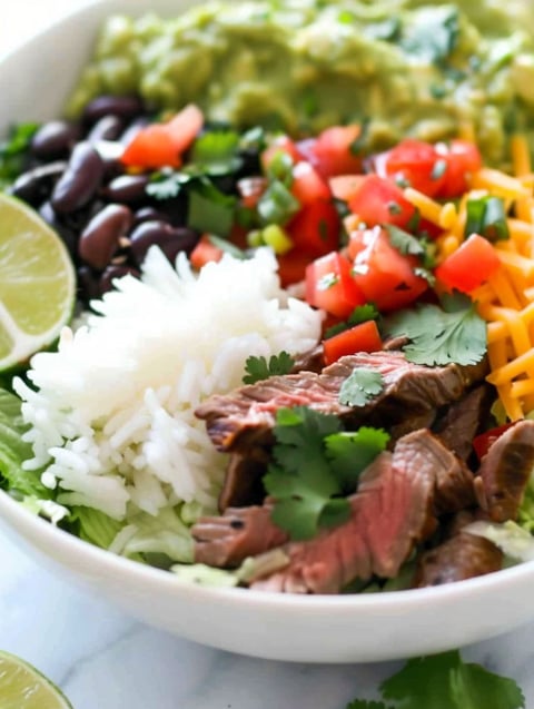 A bowl of food with rice, beans, tomatoes, and meat.