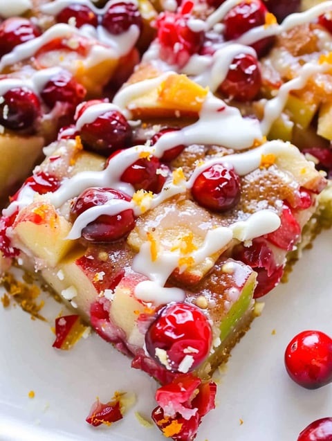 A slice of cake with white icing and red cranberries.