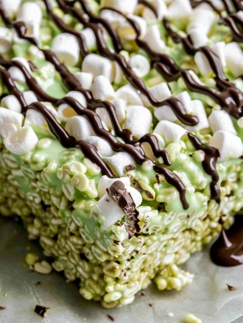 A close up of a pistachio rice krispie treat with dark chocolate drizzled on top.